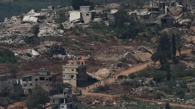 Aerial image of buildings flattened and people walking past in Lebanon.
