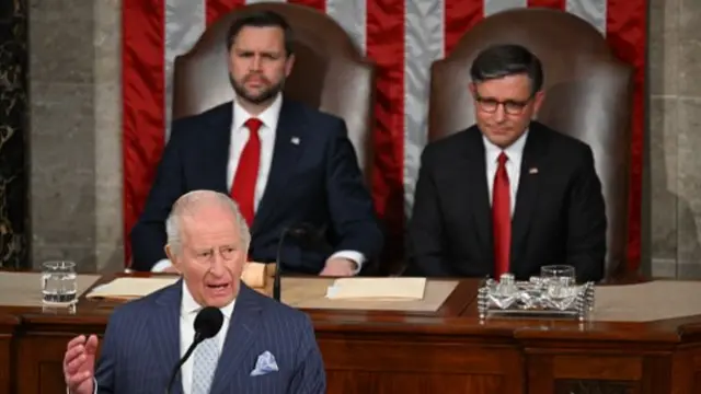 King Charles speaking at a lectern with JD Vance and Mike Johnson sitting behind.
