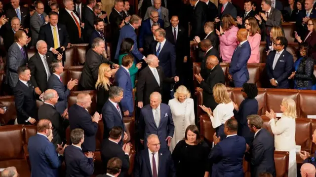 King Charles and Queen Camilla walking through Congress as people stand and applause.