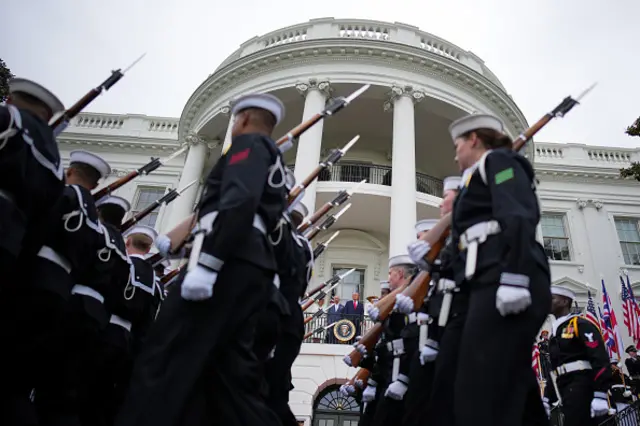 Navy personnel march with rifles slung over their shoulders outside the White House.