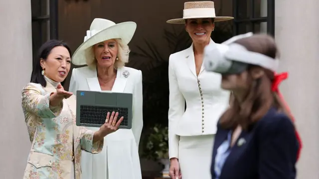 Queen Camilla and First Lady Melania Trump look on as a student wears a VR headset in front of them