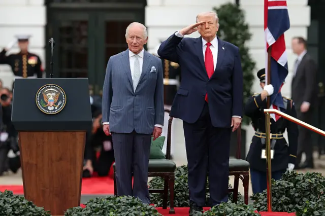 The King stands alongside Donald Trump who salutes