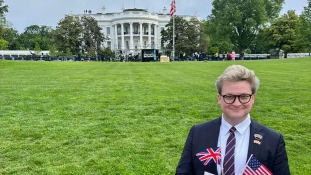 Chase Heineman standing outside the White House holding British and American flags.