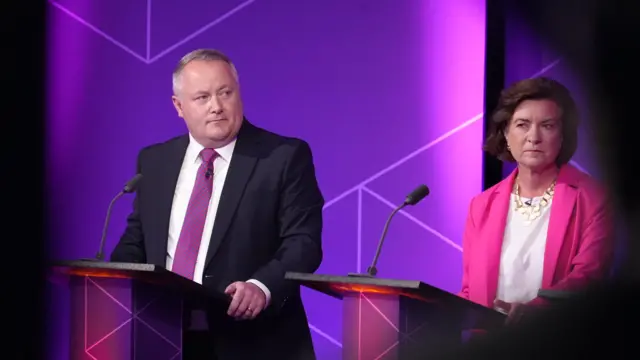 Mae Darren Millar yn sefyll y tu ôl i ddarllenfa wrth ymyl Eluned Morgan.