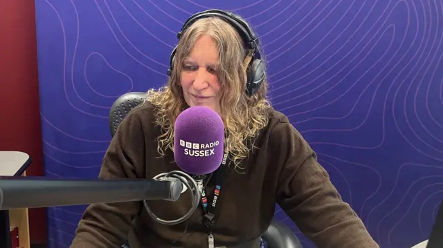 Sarah Gorrell in a radio booth in front of a microphone wearing headphones