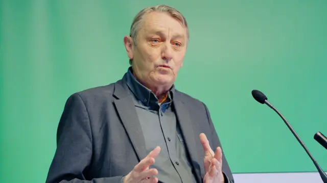 Anthony Slaughter speaking at a lectern with a microphone in front of him