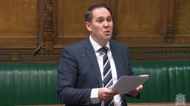 Sam Rushworth MP is a man with short brown hair, wearing a suit