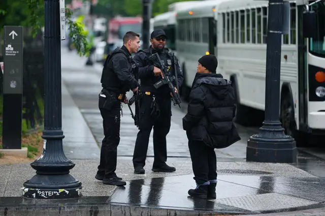 US Secret Service with large guns speaking to a pedestrian