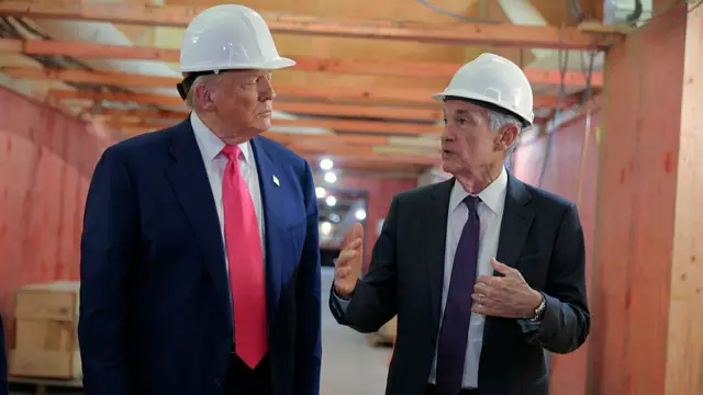 Donald and Jerome are wearing suits with ties and white hard hats inside a wood-lined hallway that is under construction.