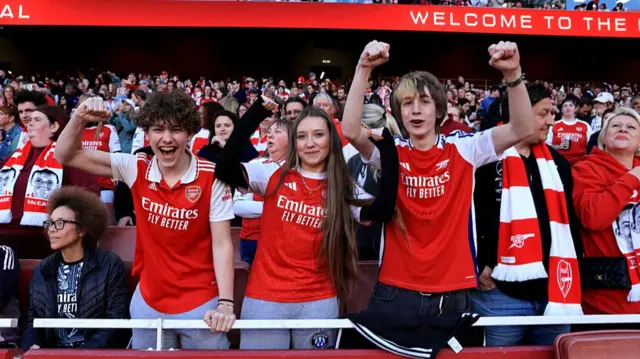 Arsenal fans raise hands in support