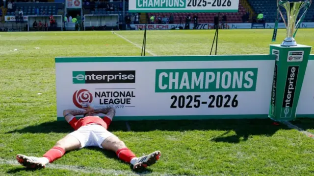 A York City footballer lies on the turf on his back after celebrating the club's promotion