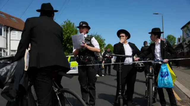 A police officer speaks to people from the cordon in Golders Green
