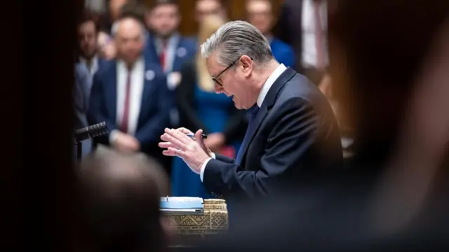 Starmer in the Commons holding his hands in the air and looking down