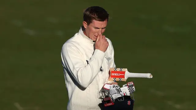 Zak Crawley walks off looking with gloves, bat and helmet in hand