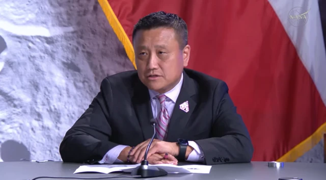 Howard Hu is seen talking behind a microphone to reporters