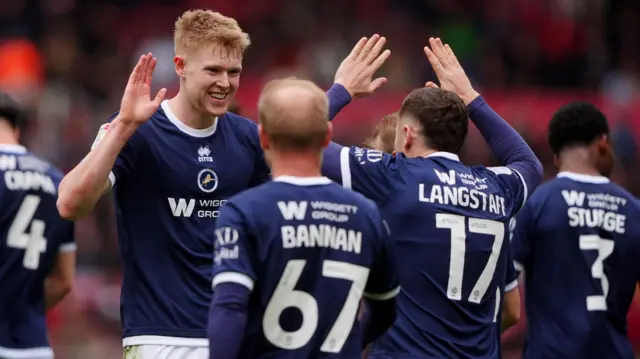 Millwall's Josh Coburn, wearing the Lions' navy blue shirt, celebrates with his team-mates with high-gives after scoring the second goal in a 2-1 win at Middlesbrough