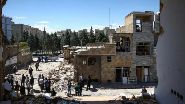 People gather outside a residential building damaged by a strike, amid the U.S.-Israeli conflict with Iran, in Karaj, Iran, April 3, 2026.