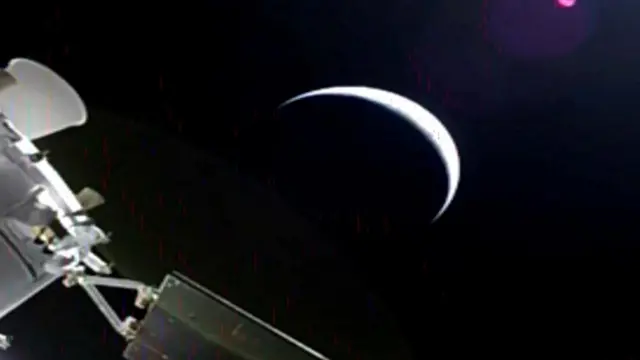 The Orion capsule leaves Earth, backlit by the sun as a crescent, on its way to fly by the moon