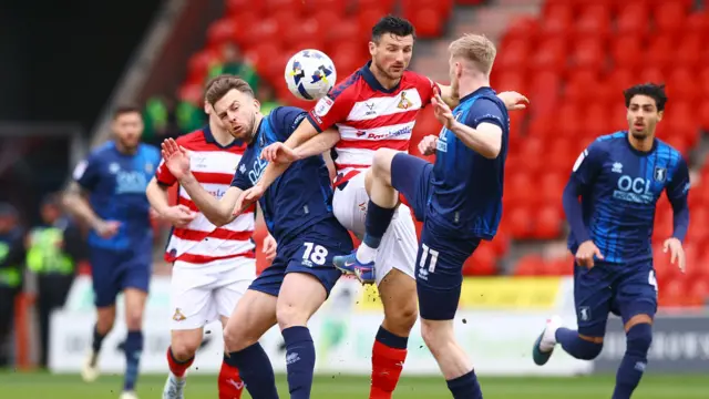 Doncaster and Mansfield players challenge for the ball