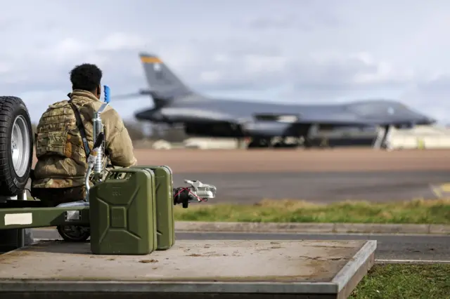 US military personnel patrol as US Air Force B-1 Lancer bomber planes get prepared for operation at RAF Fairford in the Cotswolds