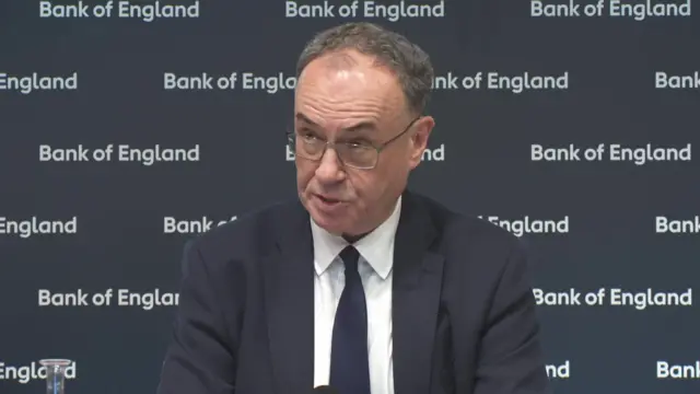 Bank of England governor Andrew Bailey in suit and tie sitting down during a press conference
