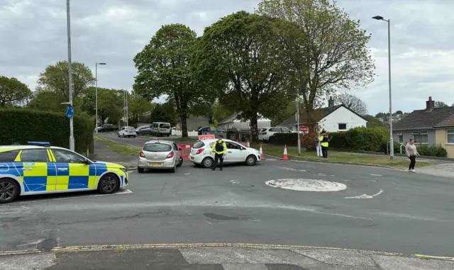 Police cars, people in hi vis at cordon