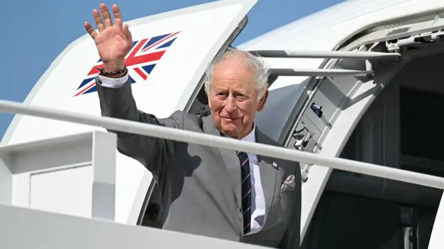 King waves from airplane stairs