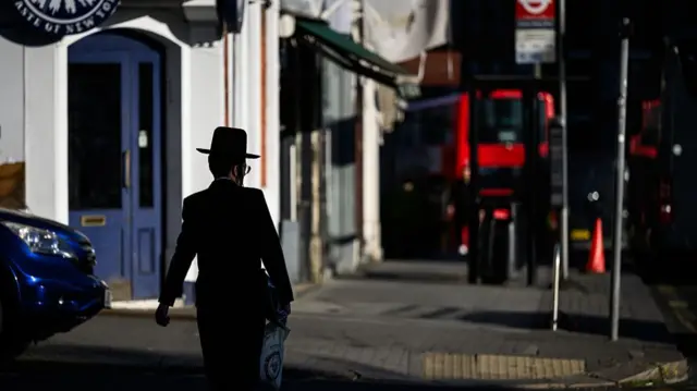 An Orthodox Jewish man walks towards the bus stop where a man was attacked on Wednesday