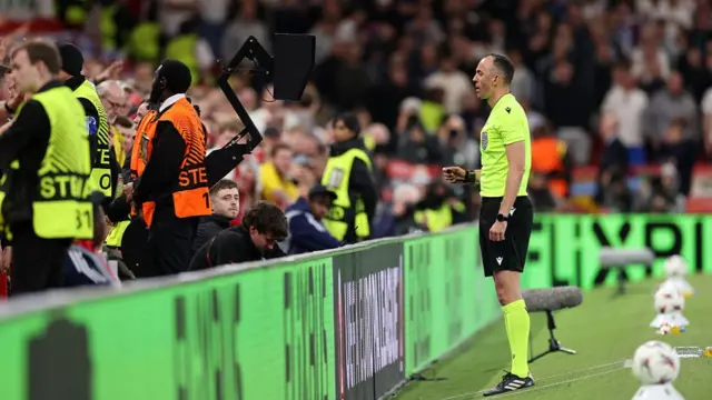 Referee Joao Pinheiro checks the VAR monitor before awarding Nottingham Forest a penalty for a handball by Lucas Digne