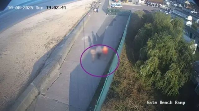 Three teenagers walk along the beach.