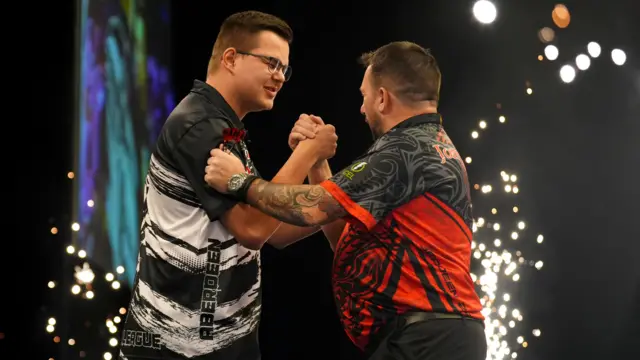 Gian van Veen (left) shakes hands with Jonny Clayton after victory in their match on night thirteen of the BetMGM Premier League 2026 at P&J Live, Aberdeen