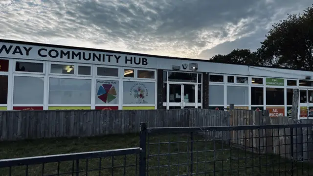 The front of the community hub. It is a white building.