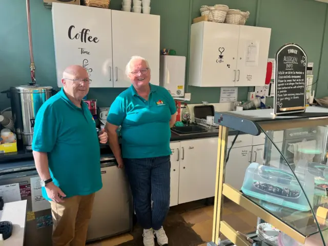 Roger and Anya stood in a kitchen space.