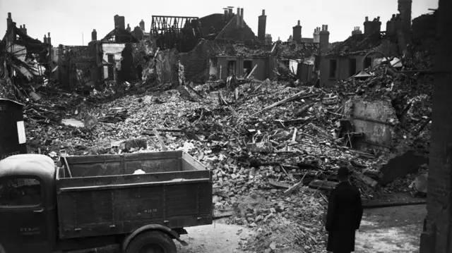 Destroyed houses with a truck and police office in the foreground