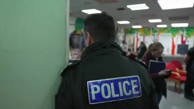 A police officer viewed from behind with blurred images of people