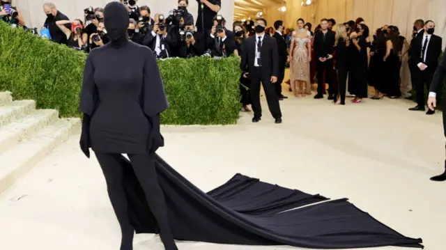 Kardashian in an all black fitted dress, covering everything from her face to her toes