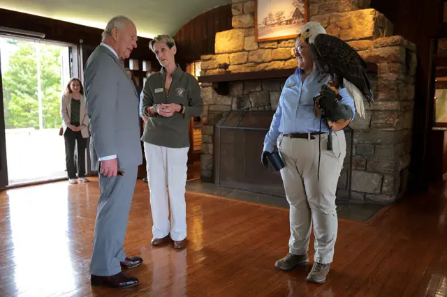 King stands next to a park employee holding a bald eagle on her hand