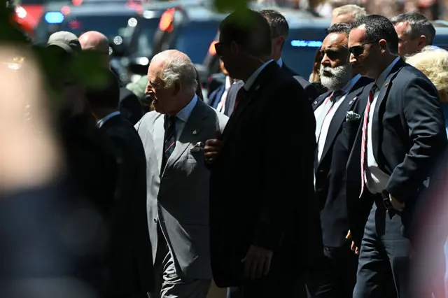 King Charles and his security detail walk down the street in Front Royal, Virginia