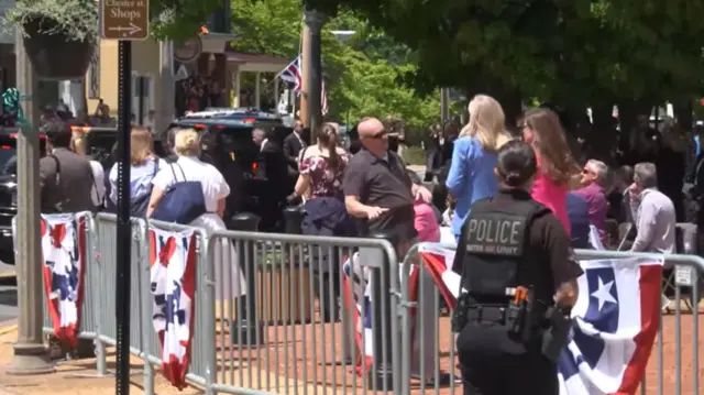 view of black SUV behind gates and crowd