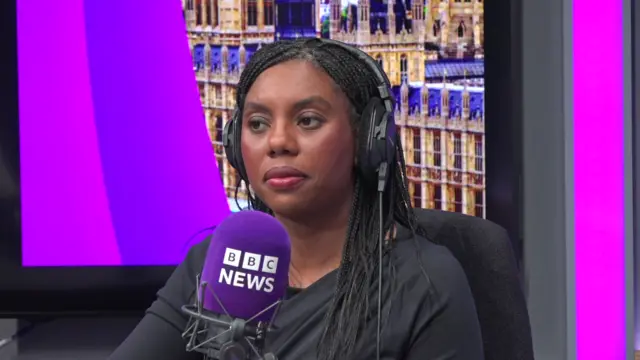 Badenoch, wearing headphones, sits in studio behind a BBC London mic
