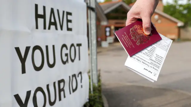A voter carrying his passport along with his poll card, as he makes his way to vote a polling station