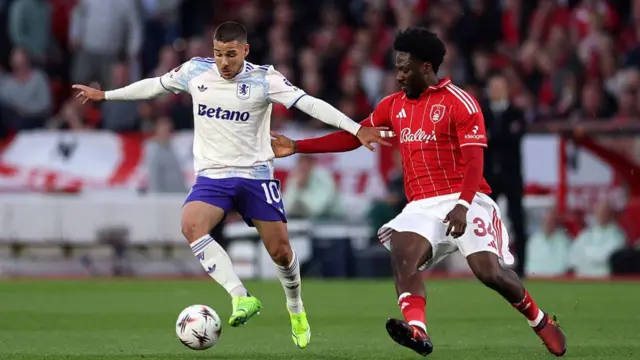 Emi Buendia of Aston Villa is challenged by Ola Aina of Nottingham Forest during the UEFA Europa League 2025/26 Semi-Final First Leg match between Nottingham Forest FC and Aston Villa FC