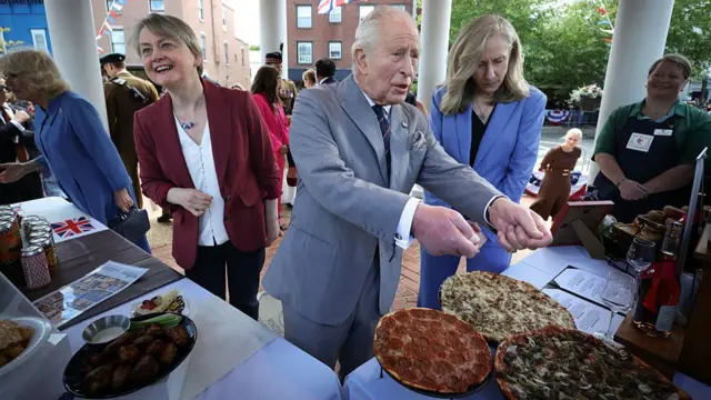 Yvette Cooper, King Charles, and Virginia governor Abigail Spanberger chat with people as pizza and snacks sit in front of them