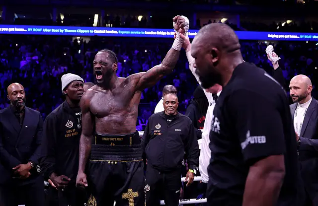 Deontay Wilder has his hand raised as Derek Chisora looks on