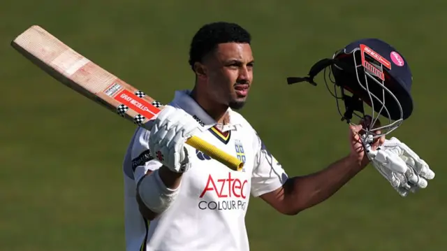 Emilio Gay raises his helmet and bat after his century for Durham against Kent
