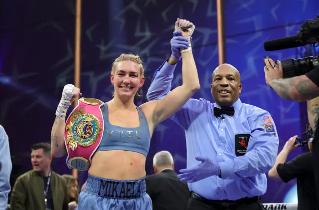 Mikaela Mayer holds the WBO welterweight title and has her arm raised by a referee