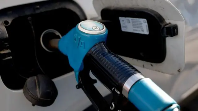 A close-up image of a fuel nozzle inserted into a vehicle's fuel tank.