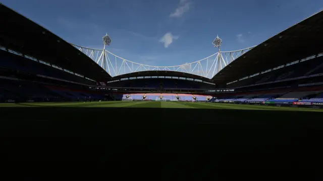 Bolton's Toughsheet Community Stadium with blue skies and sun shining at one end of the pitch and the other half of the ground in the shade