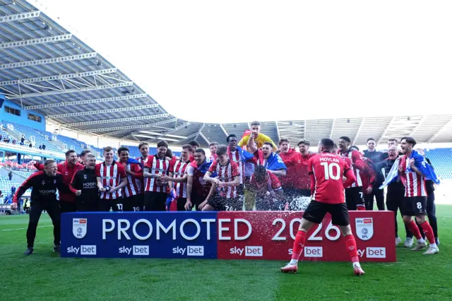 Lincoln players celebrate with a promoted 2026 sign