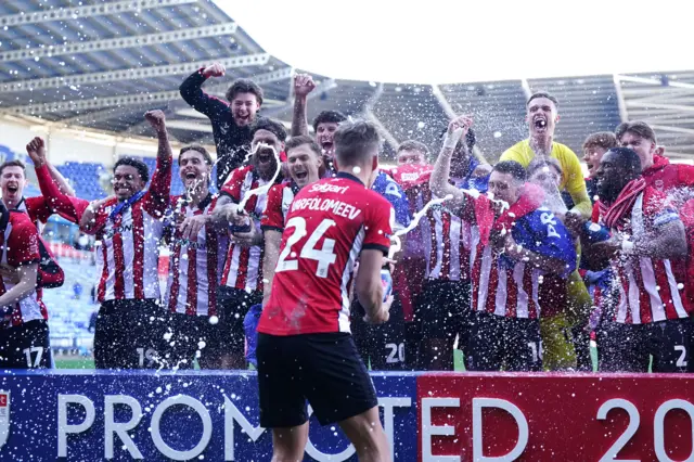 Lincoln City players celebrate with champagne